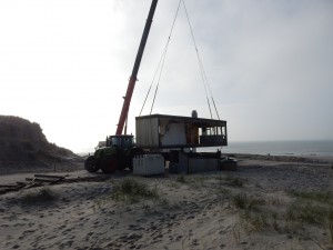 Baukran hebt Verkaufscontainer auf den Anhänger des Treckers - Saisonende auf Texel